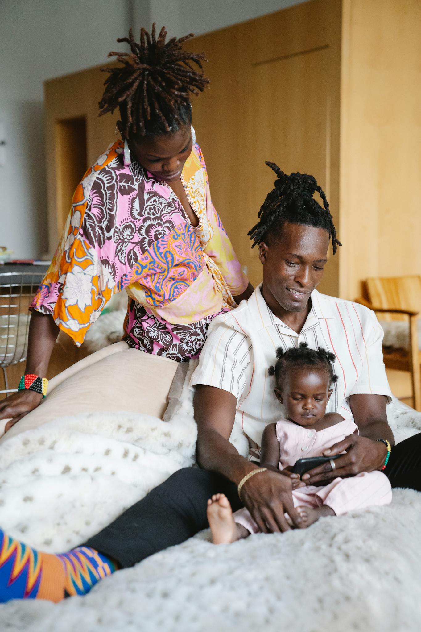 A father, a baby, and a dad enjoy quality time together indoors on a cozy couch.