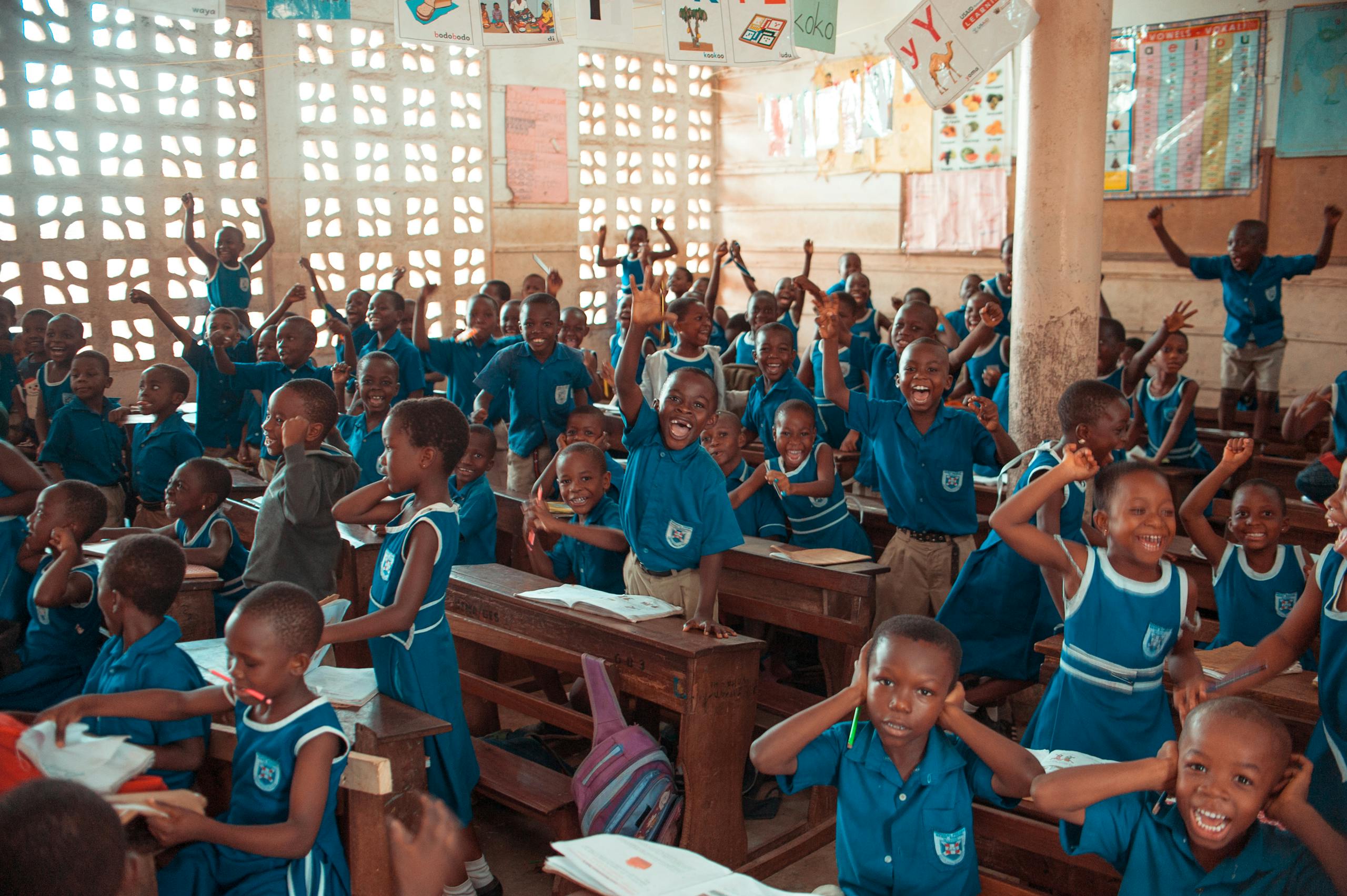 A group of schoolchildren energetically participating in a classroom activity indoors.