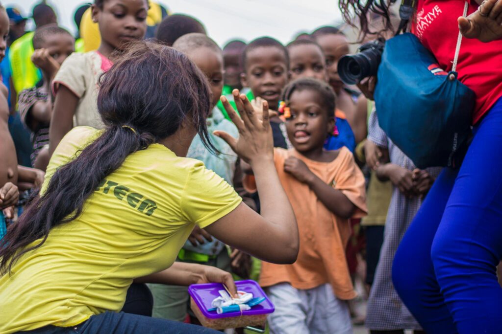 A woman engages with children through a high-five in a vibrant community setting.